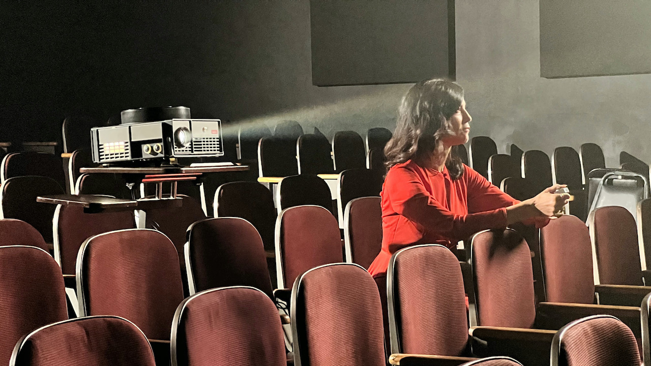 Woman sitting alone in a small theather with a pro