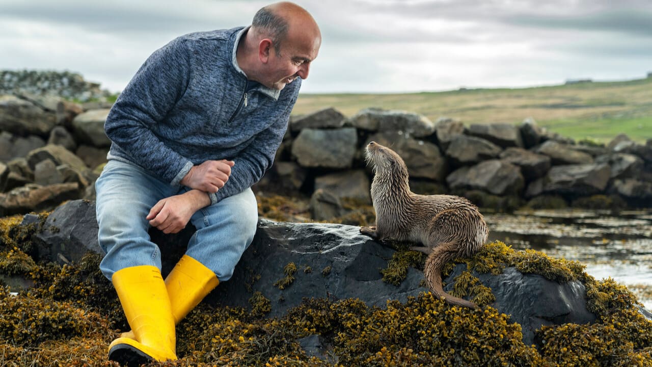 Man in rubber boots speaking to an otter