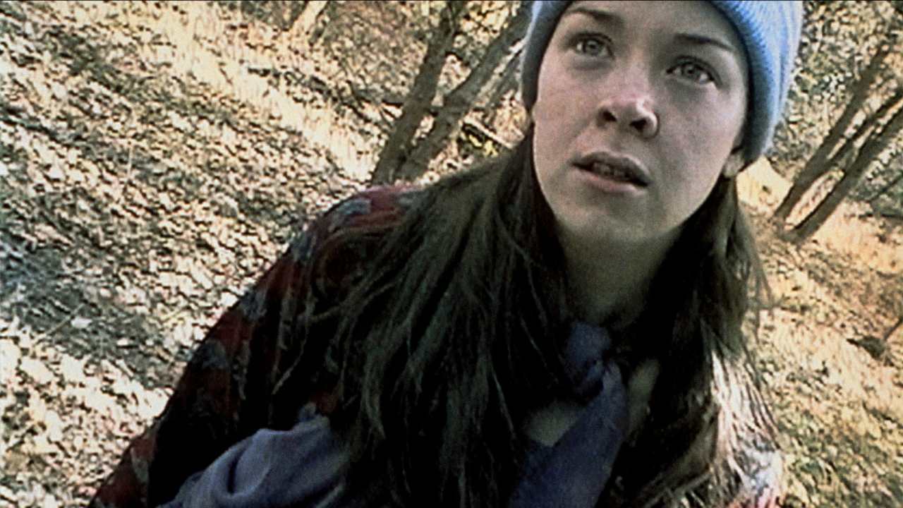 a woman in a toque standing in the woods