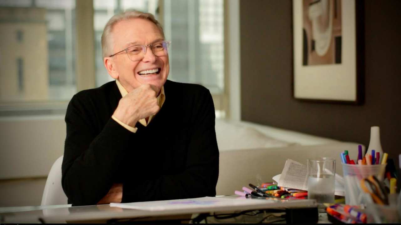 Bob Mackie smiling at a desk