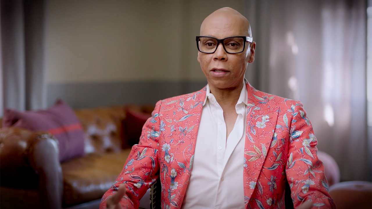 Ru Paul in a floral blazer looking at the camera