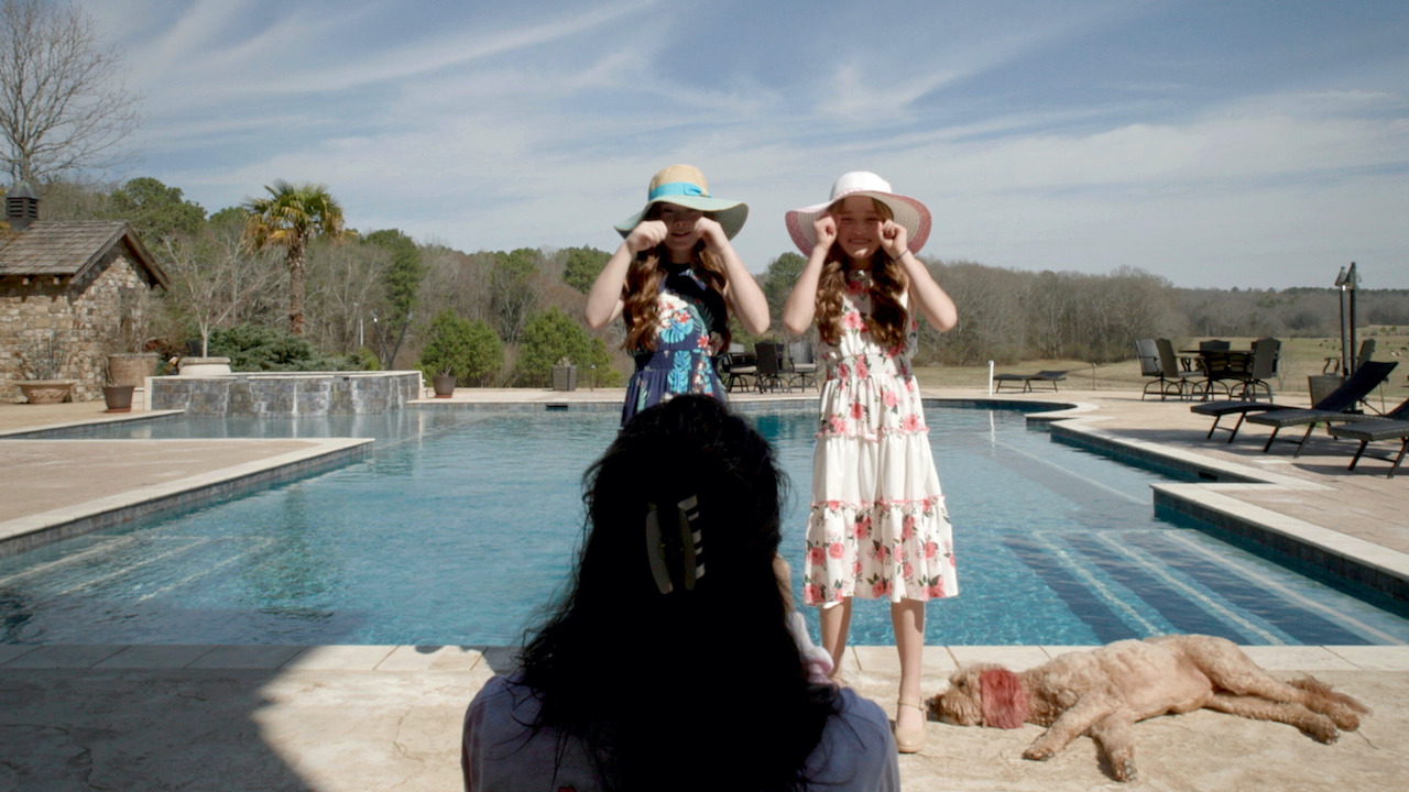 Two girls in sundresses perform in front of a pool