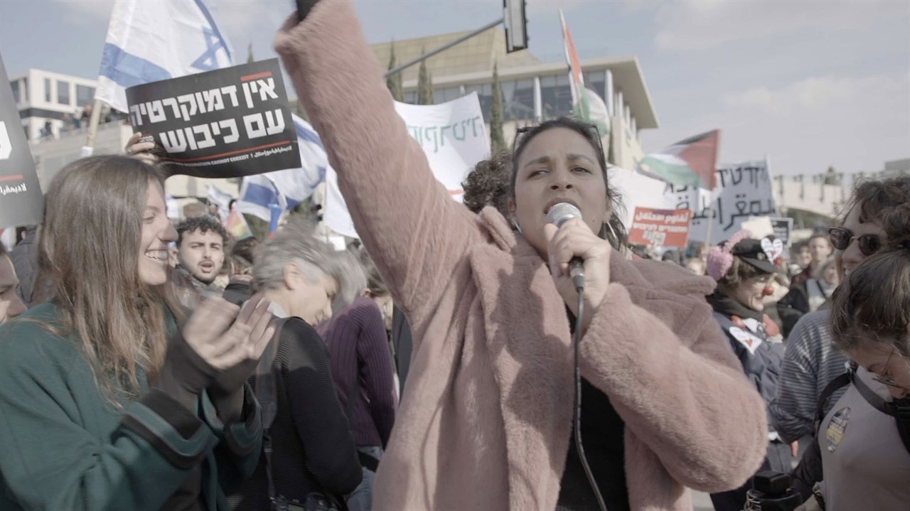 Shuster Eliassi holding a microphone at a protest
