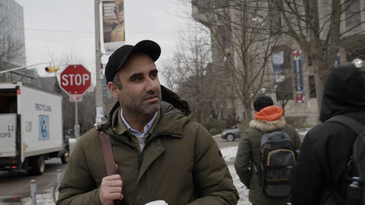 a man with a backpack next to a stop sign
