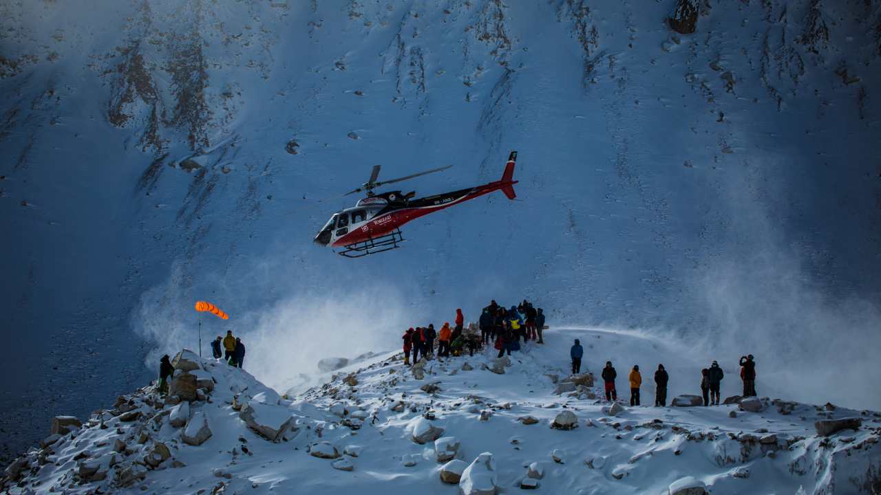 helicopter flying over people on a mountaintop