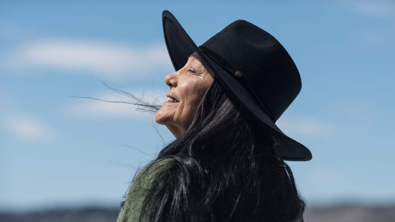 a woman smiling with a wide brim hat