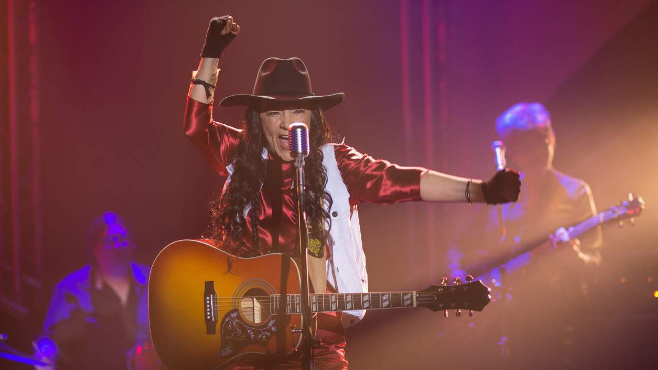 a woman with a guitar singing into a microphone