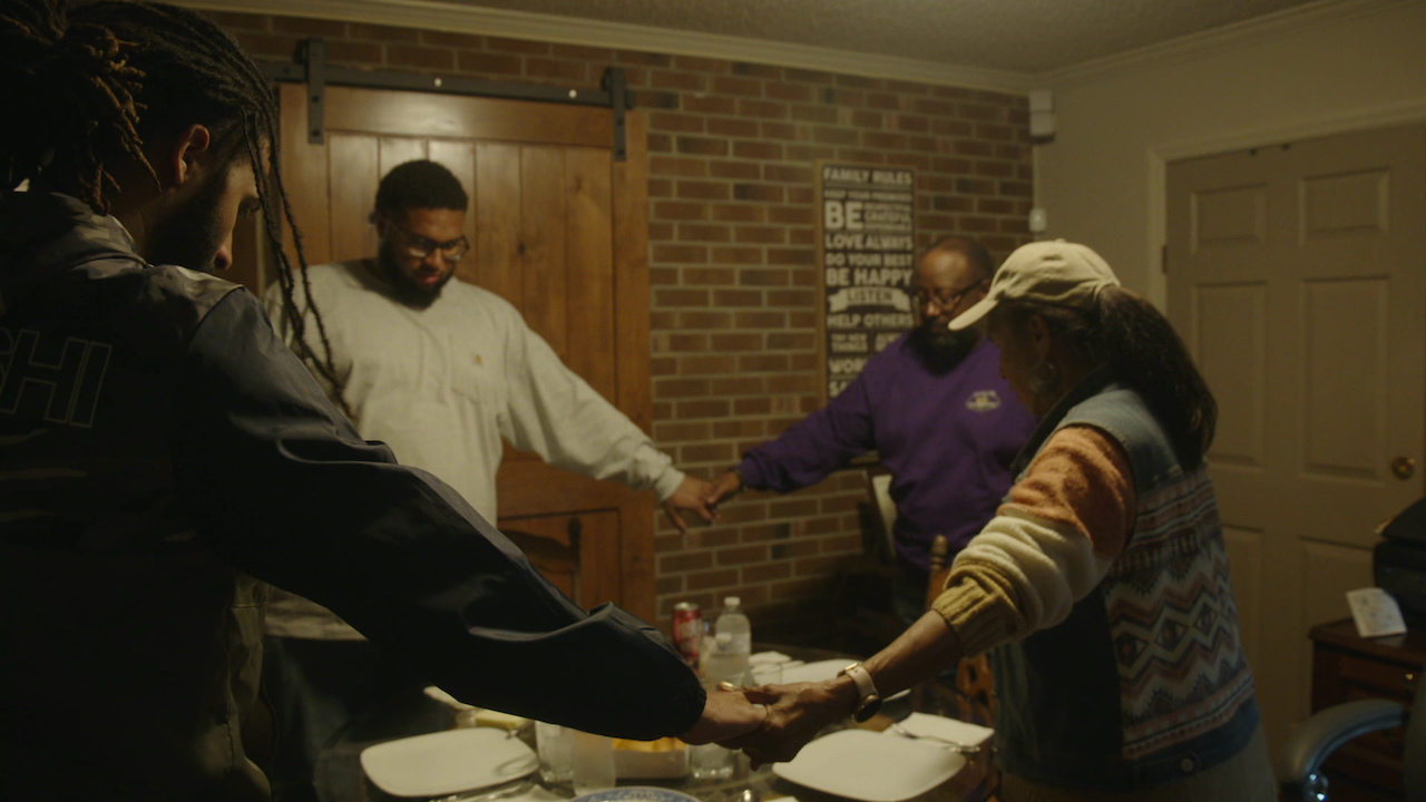 People holding hands in a circle, heads bowed in p