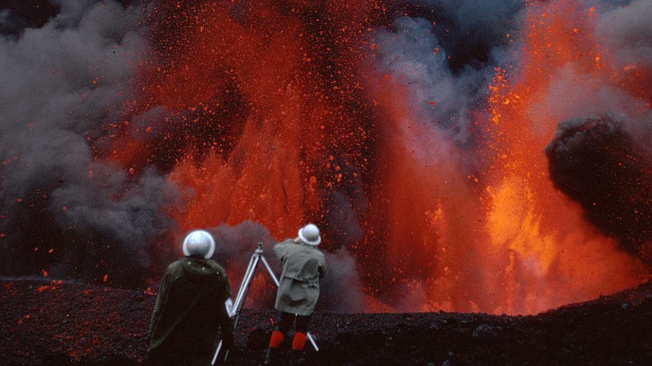 two people filmming a volcanic eruption