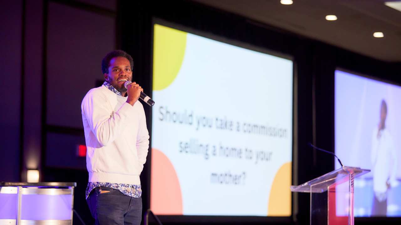 a man with a microphone in front of two screens