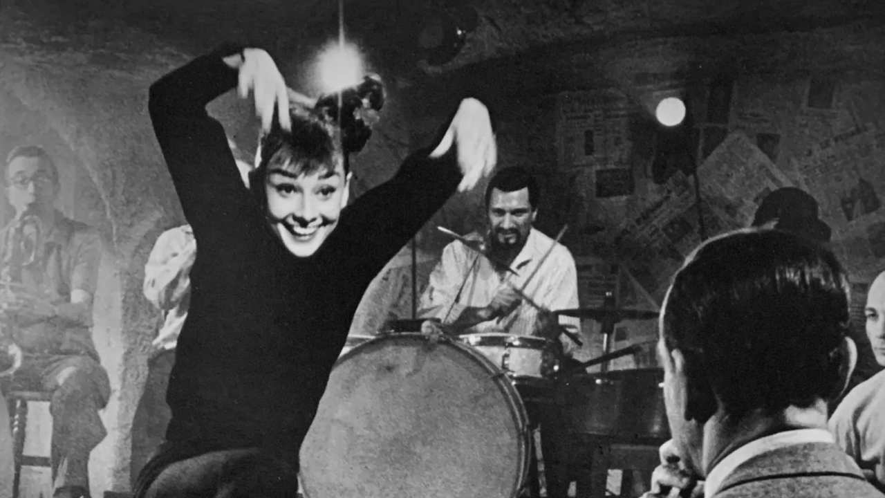 Audrey Hepburn in black dancing in front of a band