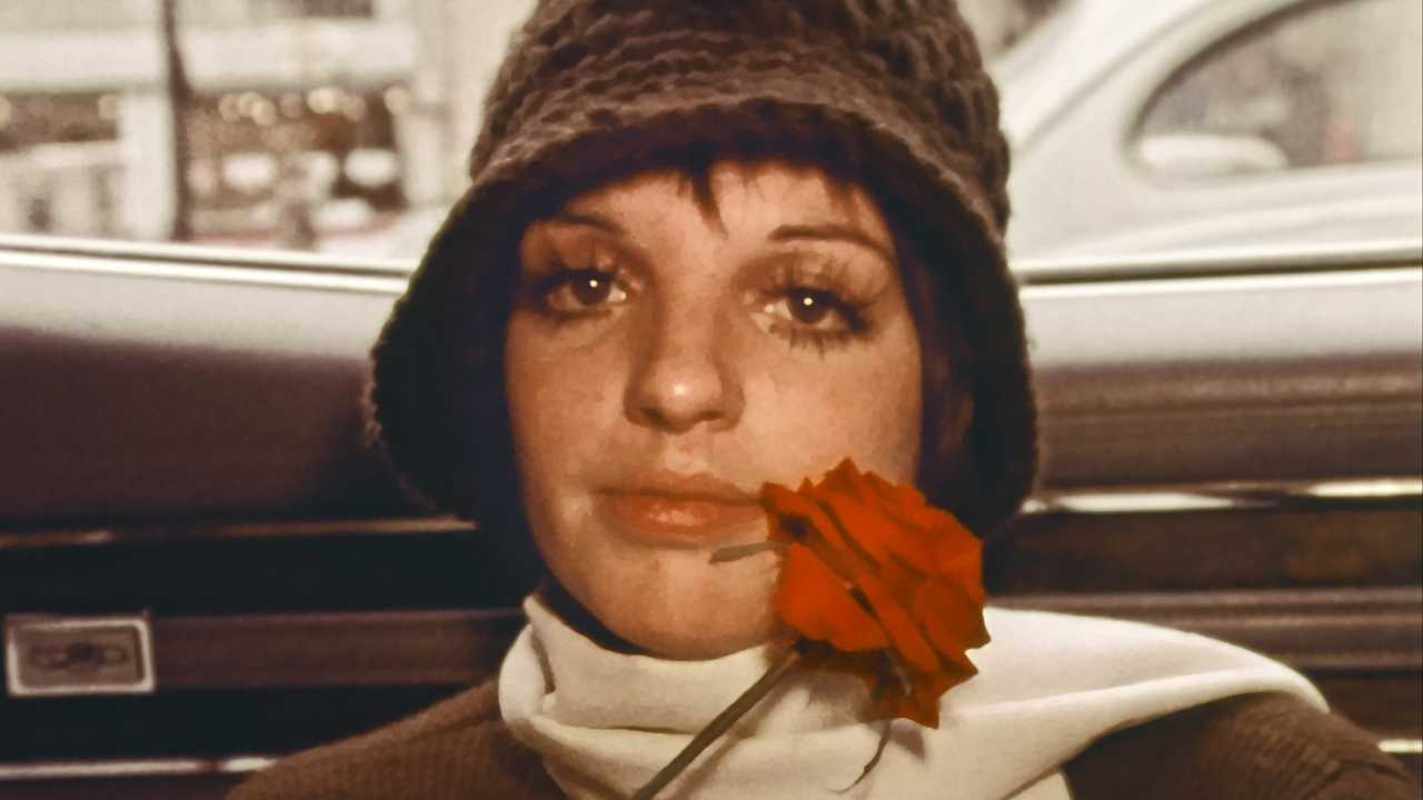 Liza Minelli with a knit hat and holding a rose