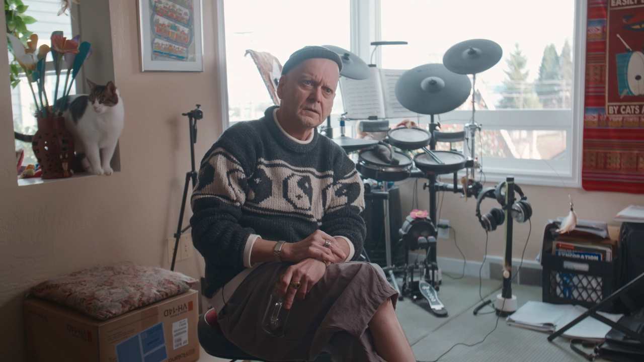 a man in a yin yang sweater in front of drums