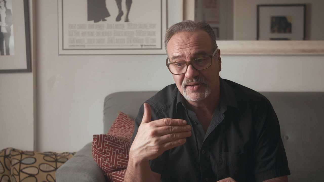 a man with glasses talking on a couch