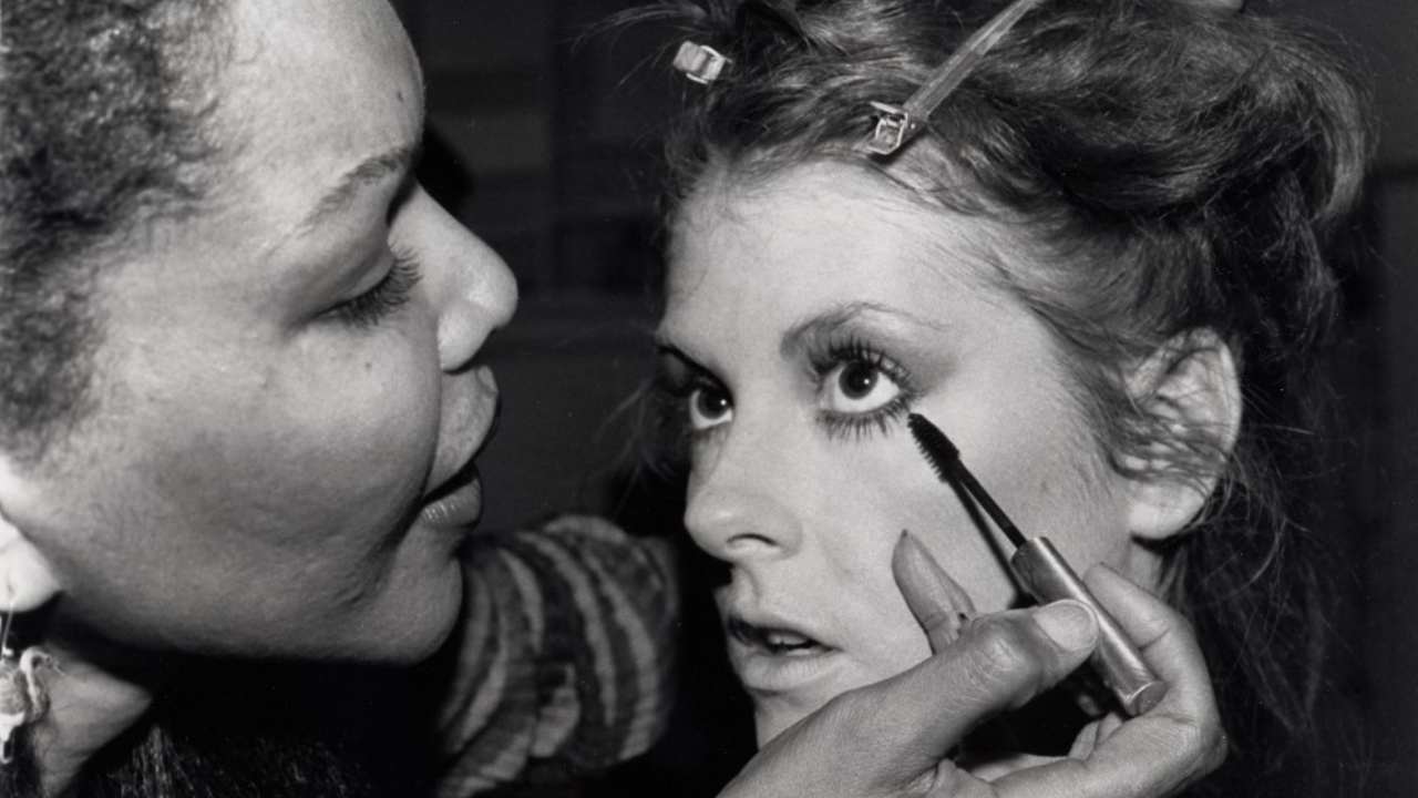 a woman putting mascara on another woman