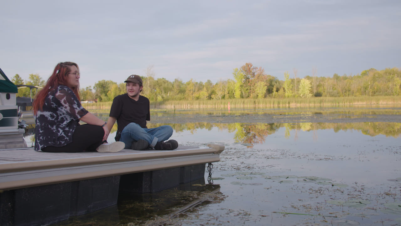 Two people sit on a floating dock