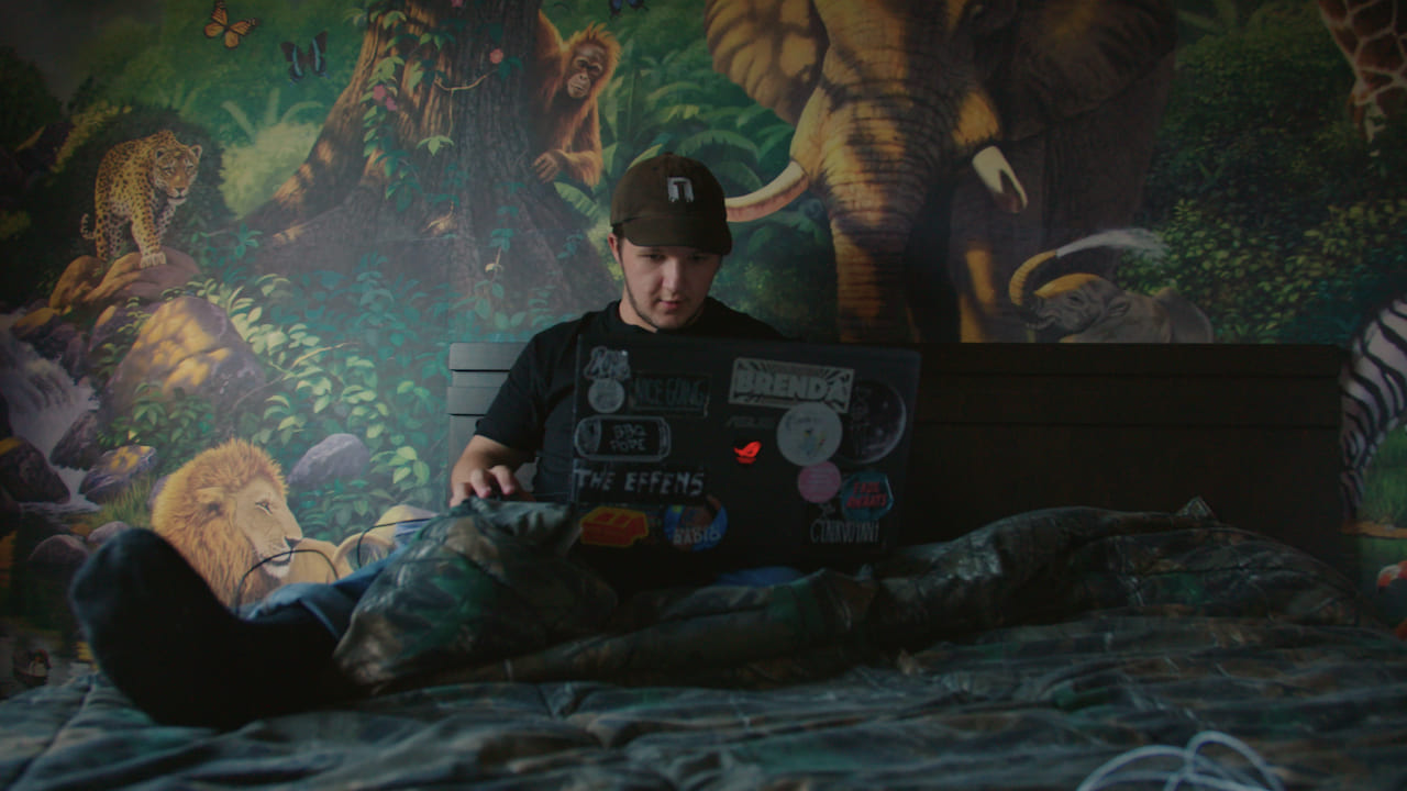 Young man sitting on a bed with a laptop