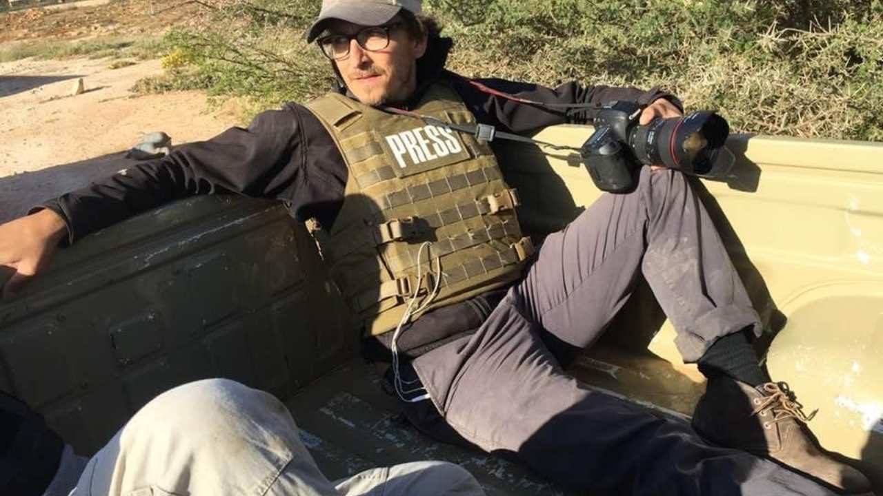 a man sitting in the back of a truck with a camera