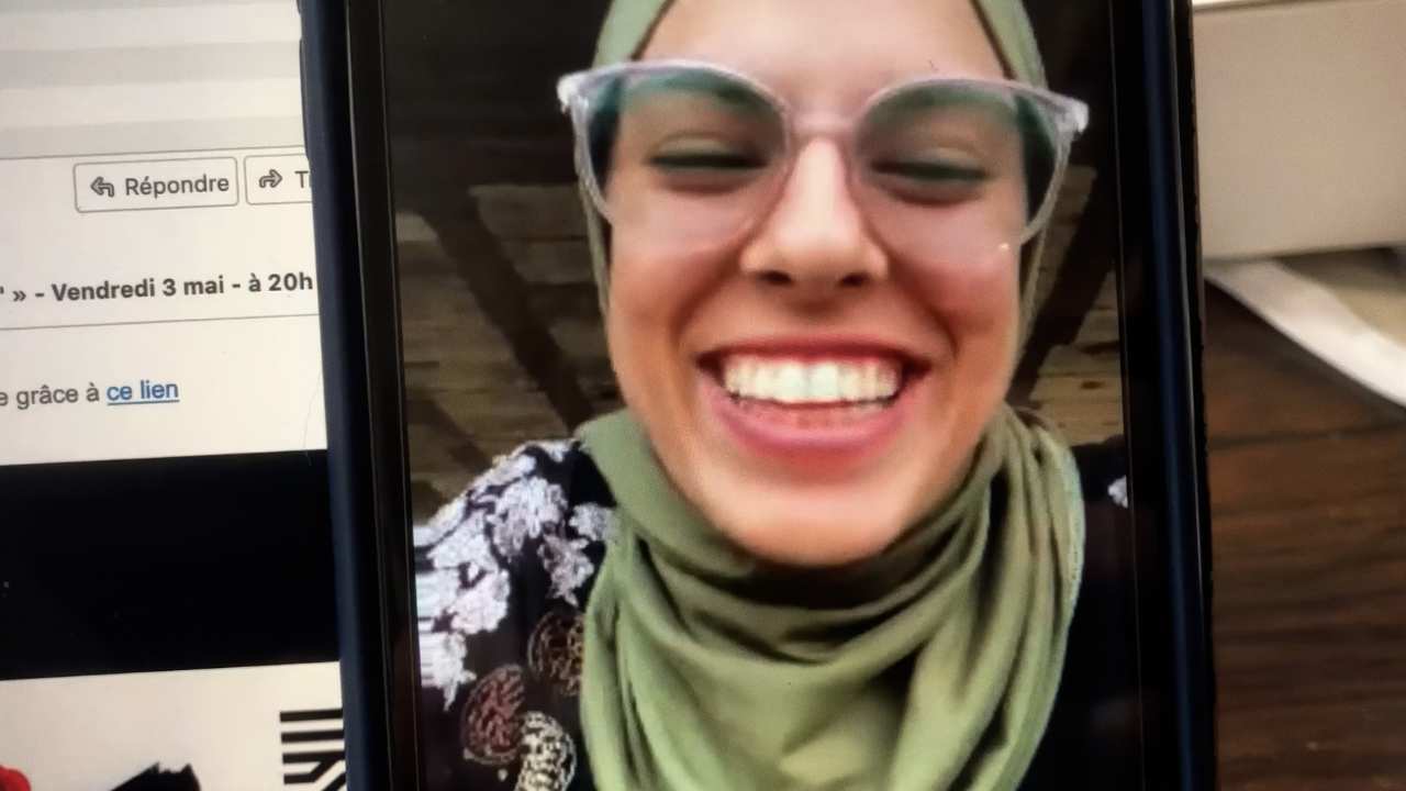a woman with a head scarf and glasses smiling