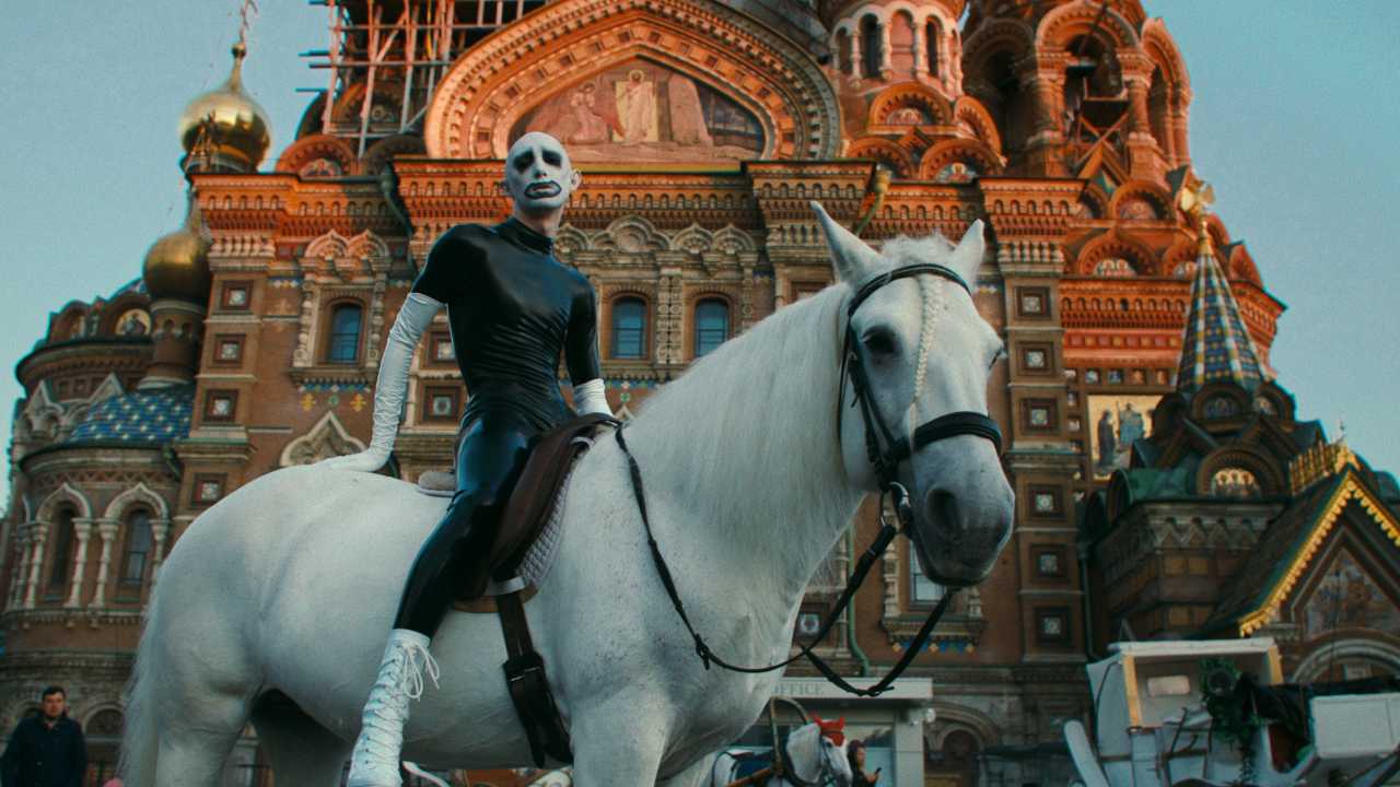 a person in a black PVC suit on a white horse