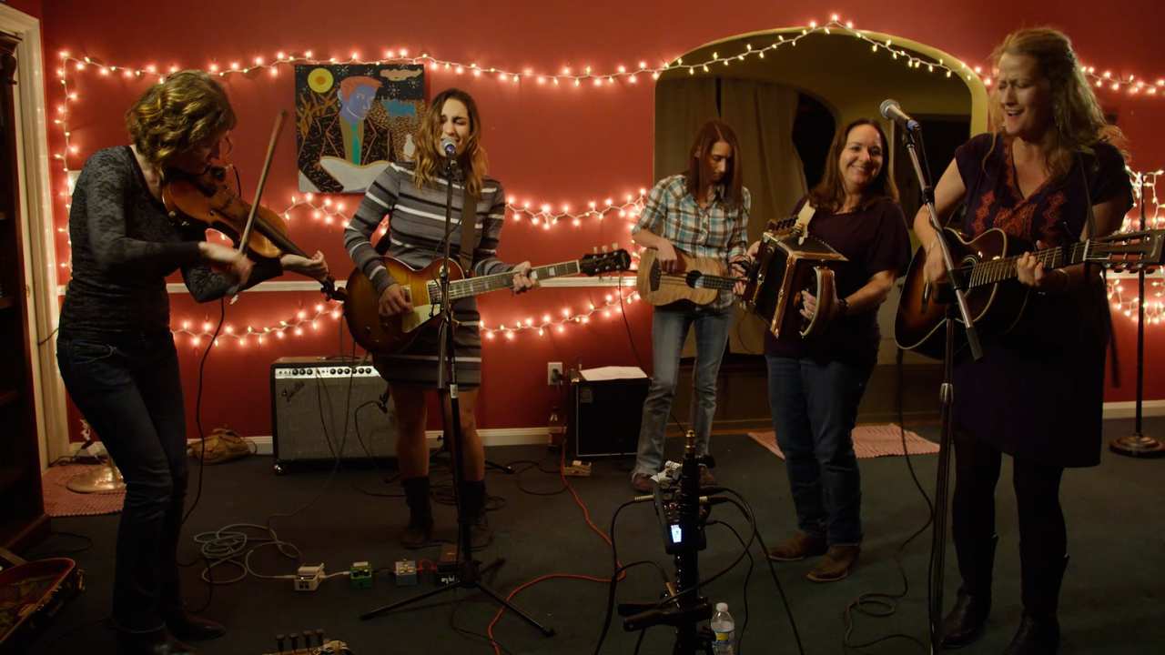 five women playing music in a room with lights