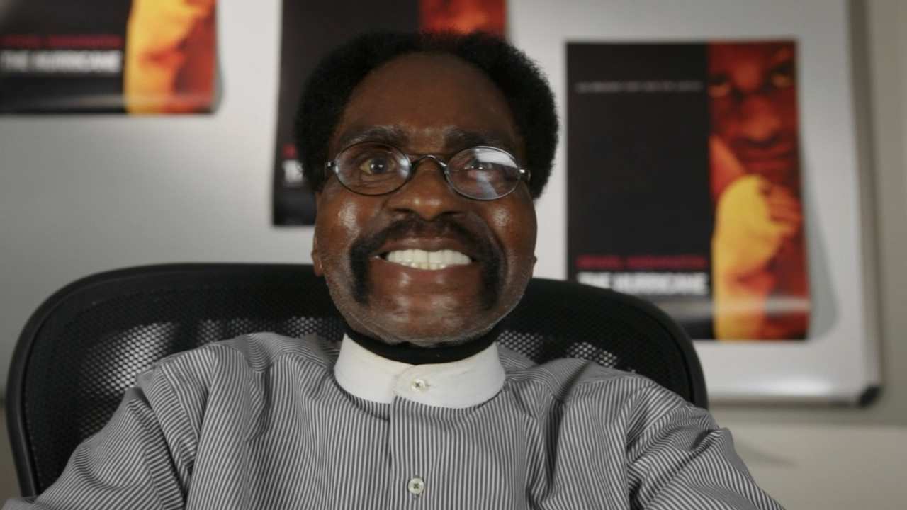 a man with glasses in a striped shirt smiling