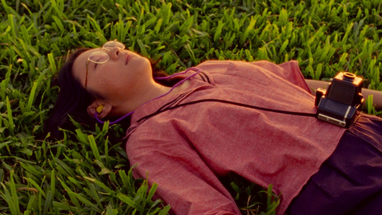 Woman laying in grass with an old fashioned camera