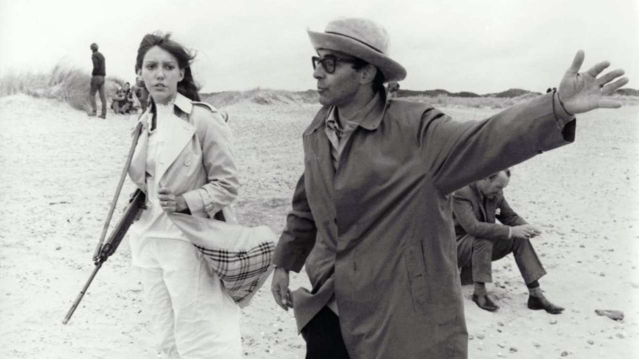 a man with glasses talking to a woman on a beach