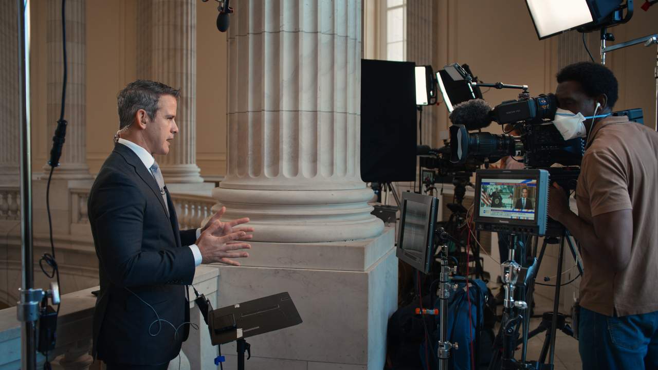 a man in a suit speaking to news cameras