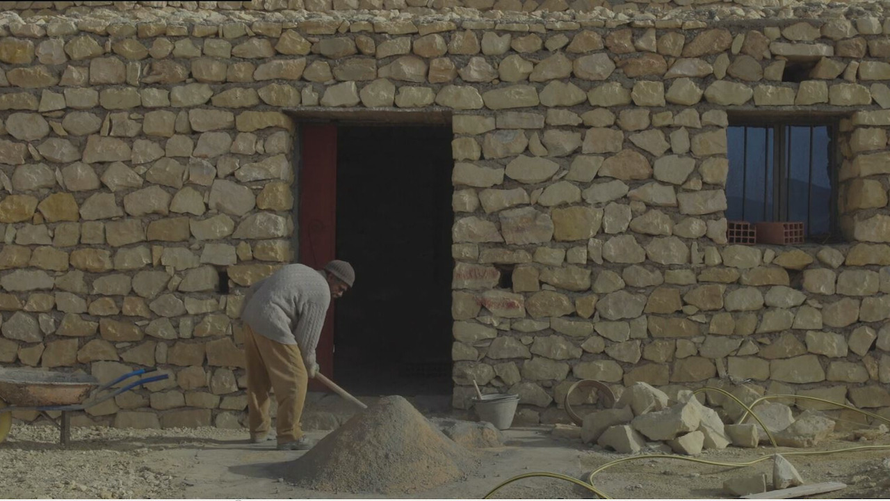 Man working outside of a stone house