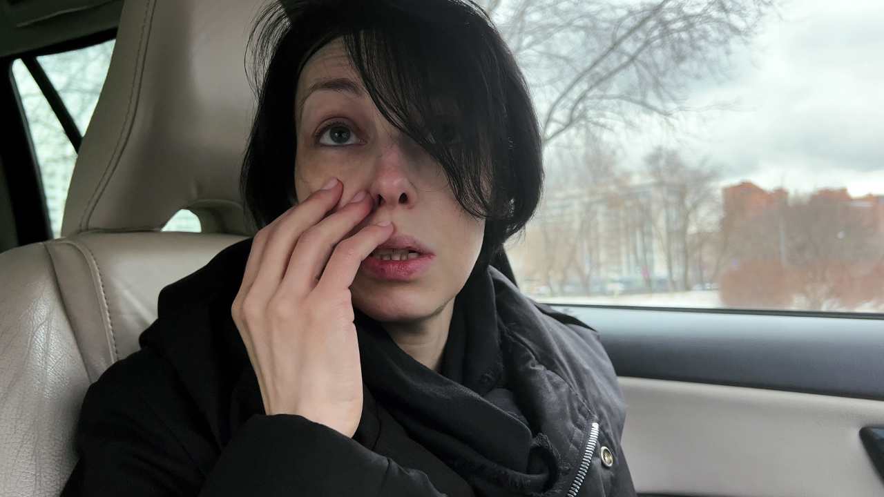 a woman in a car with her hand on her cheek