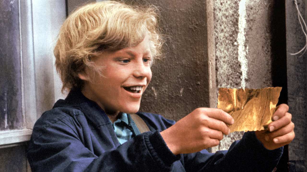 a boy smiling at a golden ticket